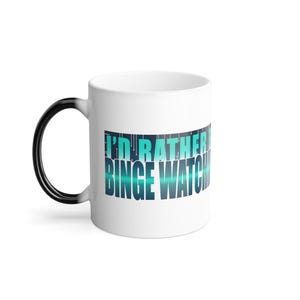 以下が含まれることがあります： 白のセラミックマグカップ。黒い持ち手が白に変わります。「I'D RATHER BINGE WATCH」の文字がターコイズブルーとブルーで表示されています。お気に入りの飲み物を飲みながらテレビを見るのに最適です。