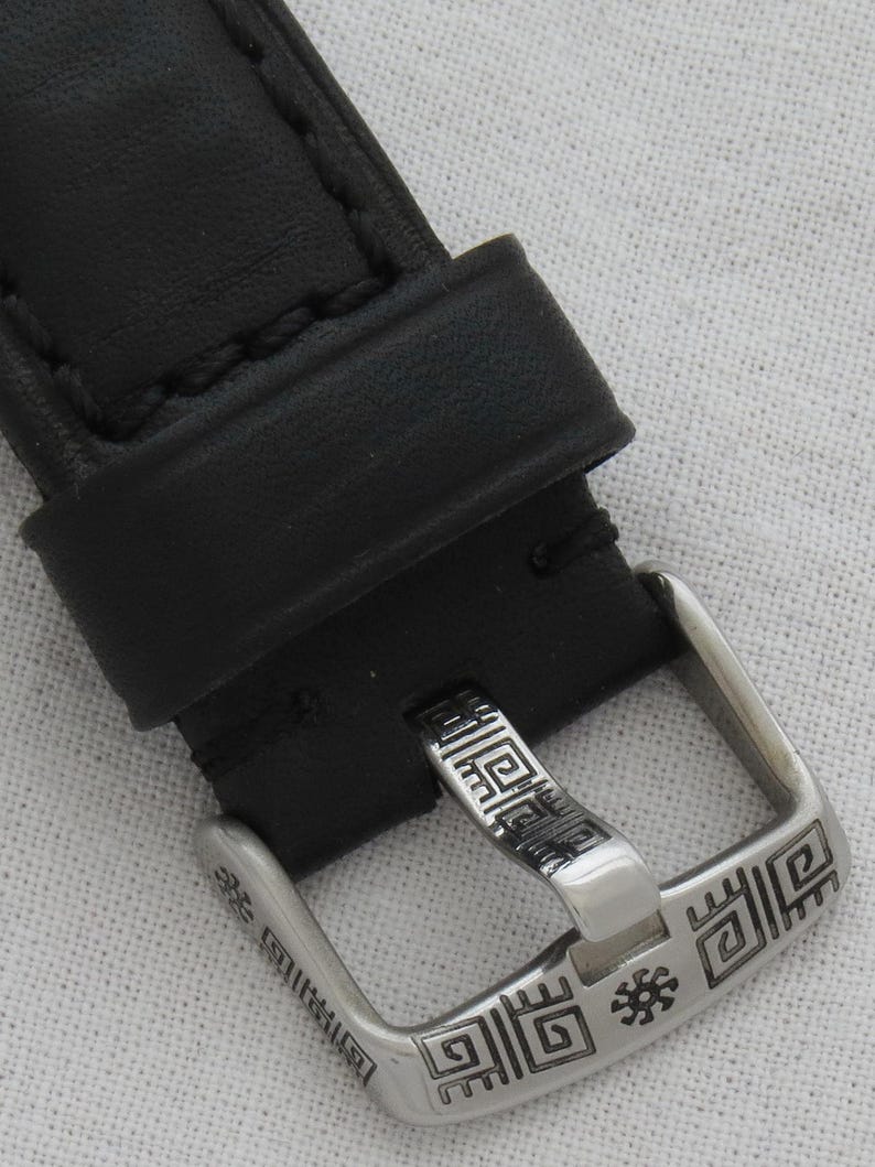 May include: A black leather watch strap with a silver buckle. The buckle has a geometric design with a small star in the center.
