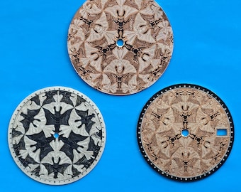 Puede incluir: Tres esferas de reloj circulares con patrones intrincados y repetitivos de murciélagos. La esfera superior es de tono cobre, la inferior izquierda es plateada y negra, y la inferior derecha es de tono cobre con un borde negro y ventana.