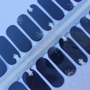 May include: A sheet of black nail wraps with white ghost and spiderweb designs. The sheet is labeled "The Delighted Daisy".