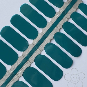 May include: Teal nail polish wraps with the text "The Delighted Daisy" on the packaging.