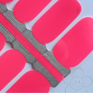 Könnte beinhalten: Nahaufnahme von leuchtend pinkfarbenen Nagellackstreifen auf einer silbernen Unterlage. Die Streifen sind in einem Muster angeordnet, mit dem Text "The Delighted DAISY" auf der silbernen Unterlage. Der Hintergrund ist weiß.