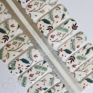 May include: Nail wraps with a festive design. Each wrap features a cream background with green holly leaves, red berries, and brown branches. The text "The Delighted Daisy" is visible on the silver backing.