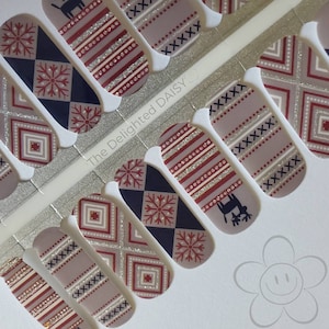May include: Nail polish wraps with a winter holiday theme. The designs feature red, white, and blue snowflakes, reindeer, and geometric patterns. The text "The Delighted DAISY" is visible on the sheet.