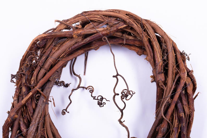 May include: A rustic, circular wreath crafted from intertwined brown vines and twigs. The wreath features a natural, organic texture with intricate details and delicate, curling tendrils, perfect for seasonal home decor.