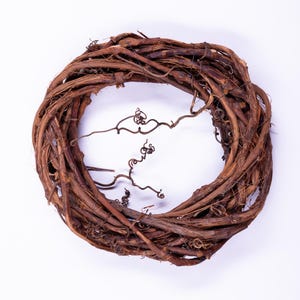 May include: A circular grapevine wreath, featuring intertwined brown branches. The wreath is set against a white background, showcasing its natural texture and form. Ideal for seasonal home decor.