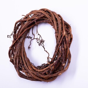 May include: A natural grapevine wreath, perfect for seasonal decor. The wreath is made of intertwined brown vines, creating a circular shape. Some vines have small, curly tendrils, adding texture and visual interest. Ideal for crafting or home decoration.