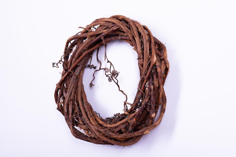 May include: A natural grapevine wreath, perfect for seasonal decor. The wreath is made of intertwined brown vines, creating a circular shape. Some vines have small, curly tendrils, adding texture and visual interest. Ideal for crafting or home decoration.