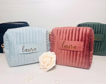 May include: Four quilted makeup bags in different colors, with the name "Laura" written in gold lettering on three of the bags.
