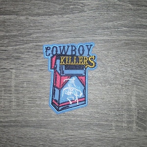 Puede incluir: Parche bordado con un diseño de paquete de cigarrillos con el texto "COWBOY KILLERS" en azul y amarillo. El paquete es rojo y azul con un gráfico de vaquero blanco. El parche tiene un borde azul claro.