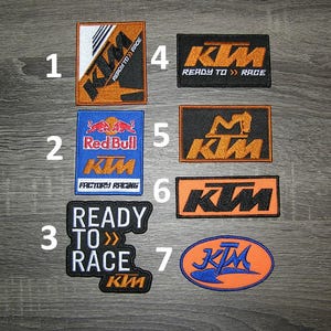 May include: Ten iron-on patches featuring the KTM logo in various colors and designs. The patches include the words "Ready to Race", "Red Bull", "Factory Racing", and "KTM".