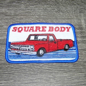 May include: Red embroidered patch with a blue border. The patch features a red pickup truck with the text "SQUARE BODY" above it.