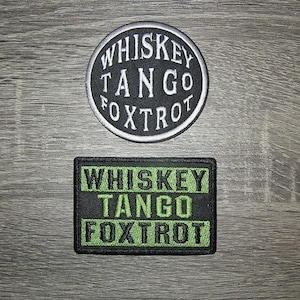 May include: Two embroidered patches with the text "Whiskey Tango Foxtrot" in black and white on a black background and in green on a black background.