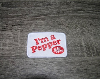 May include: White embroidered patch with red text that reads "I'm a Pepper" and a red Dr Pepper logo.