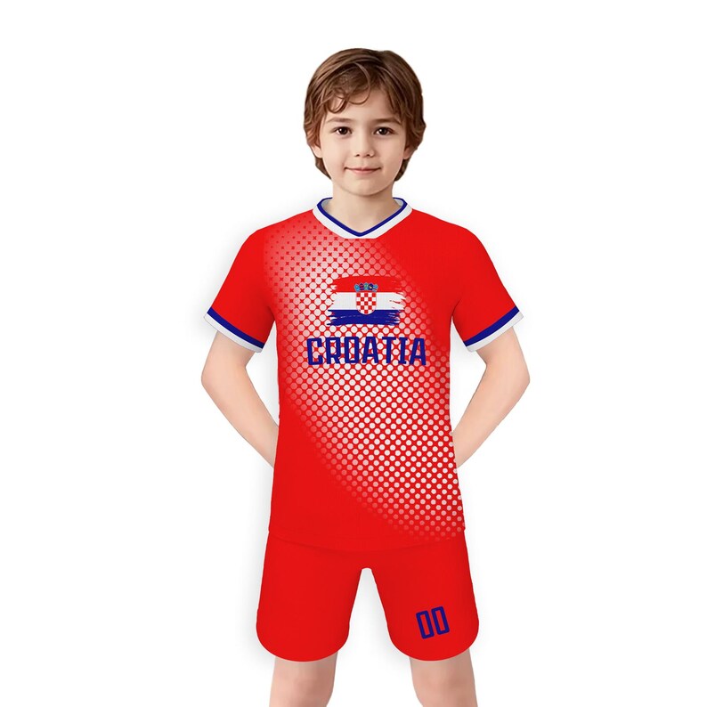 May include: A red soccer uniform with white and blue trim. The shirt features the Croatian flag and the word "CROATIA" in white. The shorts have the number "00" in blue. The uniform is worn by a young person.