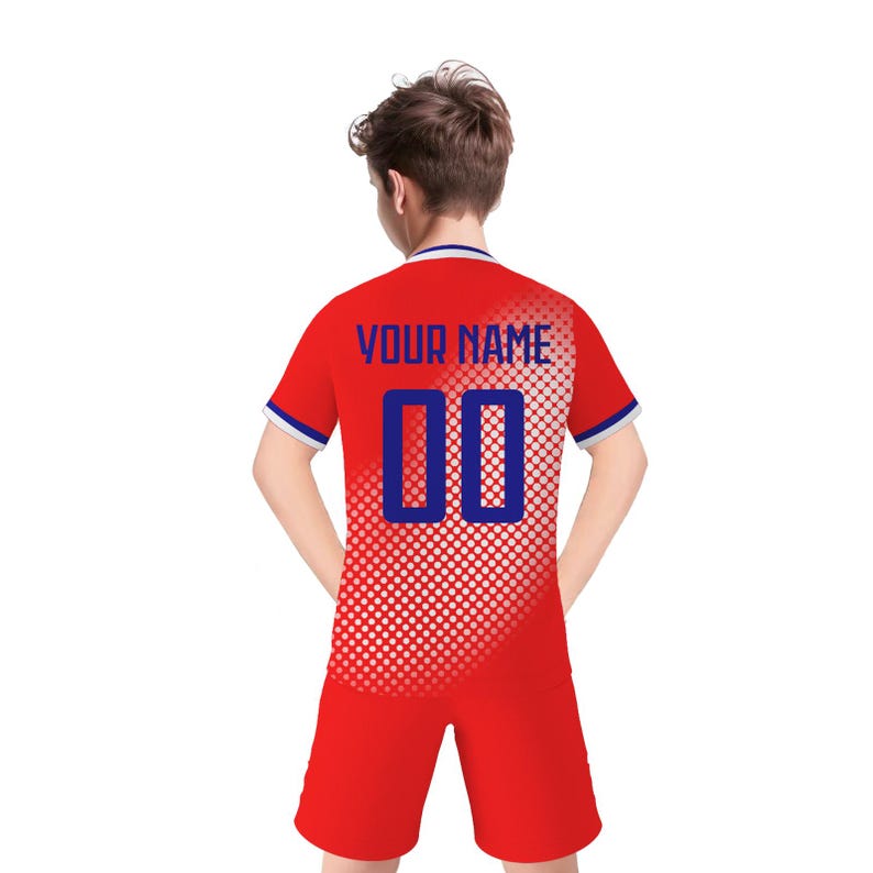 May include: Red soccer uniform with blue and white accents. The jersey features the text "YOUR NAME" above the number "00" in blue. The shorts are solid red. The uniform has a dotted pattern on the right side.