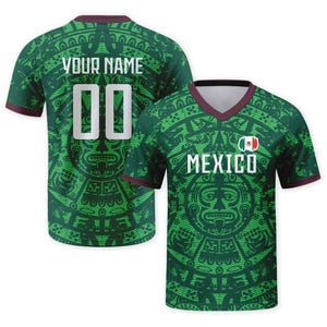 Op de afbeelding: Een groen shirt met V-hals en een ingewikkeld Azteeks kalenderpatroon. De voorkant toont de tekst MEXICO en een kleine Mexicaanse vlag. De achterkant toont de tekst YOUR NAME en het nummer 00 in het wit. De mouwen en kraag hebben donkere randen.