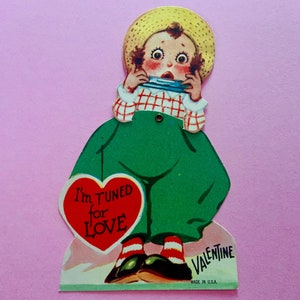 May include: A vintage Valentine's Day card featuring a cartoon boy wearing a straw hat and overalls, playing a harmonica. The card has a red heart with the text "I'm TUNED for LOVE".