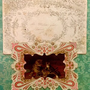 May include: An antique, ornate, paper frame with a pink and gold design. The frame contains a black and white image of two cats.