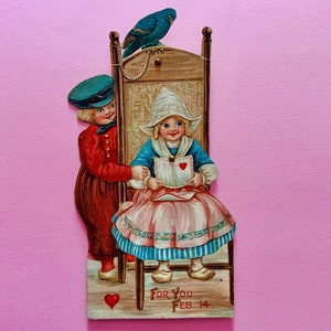 Gran tarjeta mecánica vintage para el día de San Valentín Niña y niño holandeses con loro en una cadena