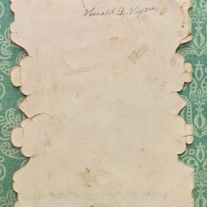 May include: A white card with a scalloped edge and the handwritten signature "Gerald D. Heyzer".