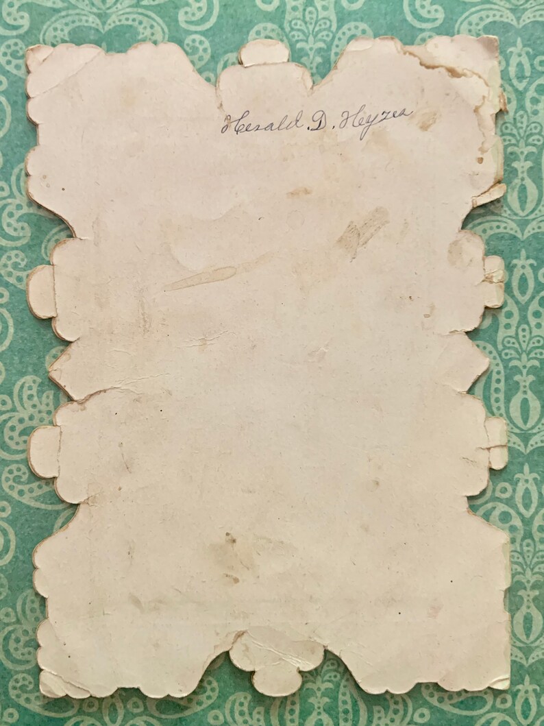 May include: A white card with a scalloped edge and the handwritten signature "Gerald D. Heyzer".