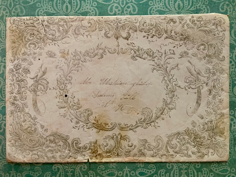 May include: An antique, off-white paper with a decorative border of intricate floral designs and a bird. The paper has a handwritten inscription that reads "Mrs. Whittington's address, Johnsonville, South Carolina."