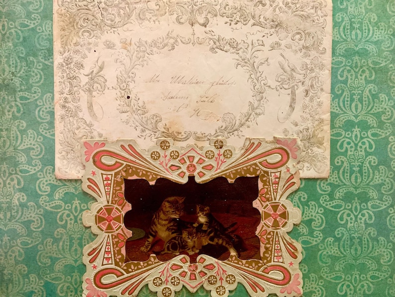 May include: An antique, ornate, paper frame with a pink and gold design. The frame contains a black and white image of two cats.