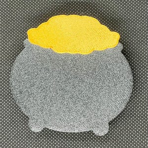 May include: A gray cauldron with a yellow felt top. The cauldron is a decorative item and is made of fabric.