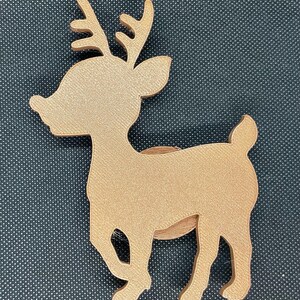 May include: A gold-colored reindeer figurine with a simple design. The reindeer is standing on a black surface.