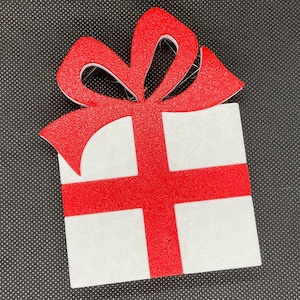 May include: A white gift box with a red bow. The box is decorated with a red ribbon and a red bow.