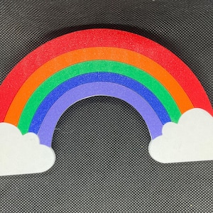 May include: A colorful rainbow made of felt with white clouds on either end. The rainbow is red, orange, yellow, green, blue, and purple.