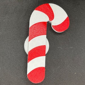 May include: A red and white candy cane ornament with a white background.