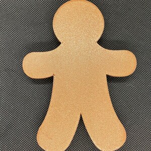 May include: A gingerbread man cookie cutter made of gold-colored metal.