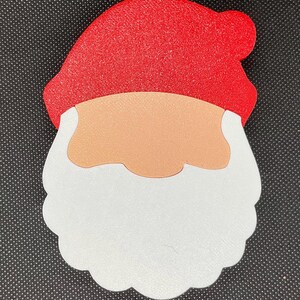 May include: A red felt Santa Claus head cutout with a white beard and a peach-colored face.