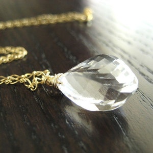 以下が含まれることがあります： 金色のチェーンネックレスに、透明な水晶のペンダントがついたもの。水晶はファセットカットされており、涙の形をしています。