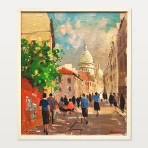 Könnte beinhalten: Ölgemälde einer europäischen Straßenszene mit Menschen. Das Gemälde zeigt Gebäude mit roten Dächern, eine Kuppelkirche und einen blauen Himmel mit Wolken. Das Kunstwerk ist in einem weißen Holzrahmen gerahmt.