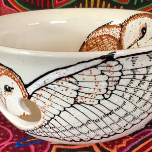 Op de afbeelding: Witte keramische garenkom met een geschilderd schuuruil-ontwerp. De uil is bruin en wit met zwarte ogen en een gevlekt vleugelpatroon.
