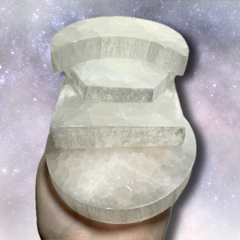 K&ouml;nnte beinhalten: Eine wei&szlig;e Kristallskulptur mit halbkreisf&ouml;rmiger Basis und abgestuften Ebenen. Der Kristall hat eine strukturierte Oberfl&auml;che und wird in einer Hand vor einem Sternenhintergrund gehalten. Das Design ist geometrisch und abstrakt.