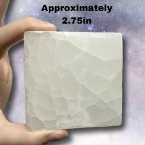 K&ouml;nnte beinhalten: Ein quadratischer, cremefarbener Steinblock, ca. 7 cm gro&szlig;, mit strukturierter Oberfl&auml;che. Der Block wird in einer Hand vor einem verschwommenen, sternenklaren Hintergrund gehalten. Der Text "Approximately 2.75in" ist sichtbar.