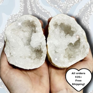 May include: Two halves of a geode, held in open hands, revealing a sparkling white crystal interior. The outer shell is a light tan color. The image includes text in a heart-shaped graphic that reads "All orders $35+ Free Shipping!"