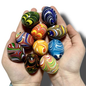 May include: A collection of ten colorful, swirl-patterned glass marbles. The marbles are arranged in a hand, with the tips of the fingers visible.