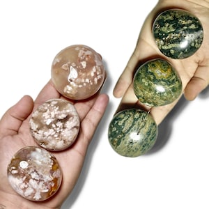 May include: Four polished gemstone spheres, two are green with white and brown markings, and two are pink with white markings.