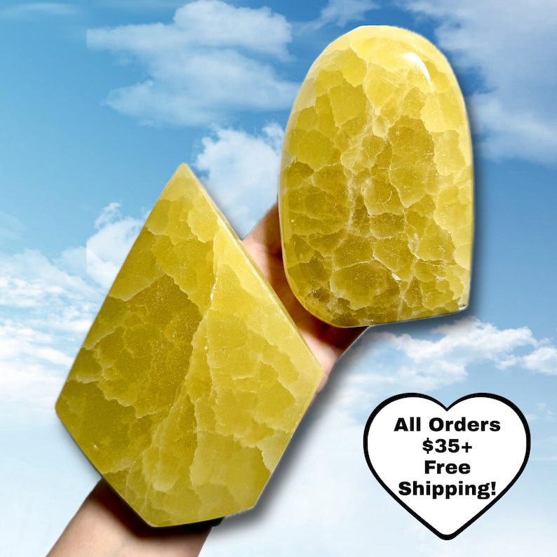 May include: Two yellow-green gemstone sculptures with a textured surface. One is a rounded shape, the other is a diamond shape. The background is a blue sky with clouds. The image includes the text "All Orders $35+ Free Shipping!"