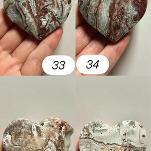 May include: Four heart-shaped stones with unique patterns and colors. The stones are held in hands and numbered 33, 34, 35, and 36. The stones have a mix of red, white, gray, and brown hues, with visible veining.