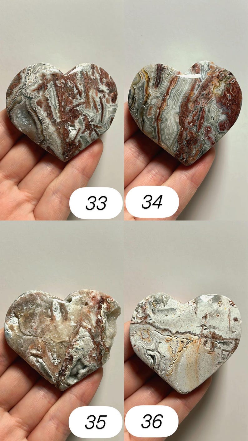 May include: Four heart-shaped stones with unique patterns and colors. The stones are held in hands and numbered 33, 34, 35, and 36. The stones have a mix of red, white, gray, and brown hues, with visible veining.