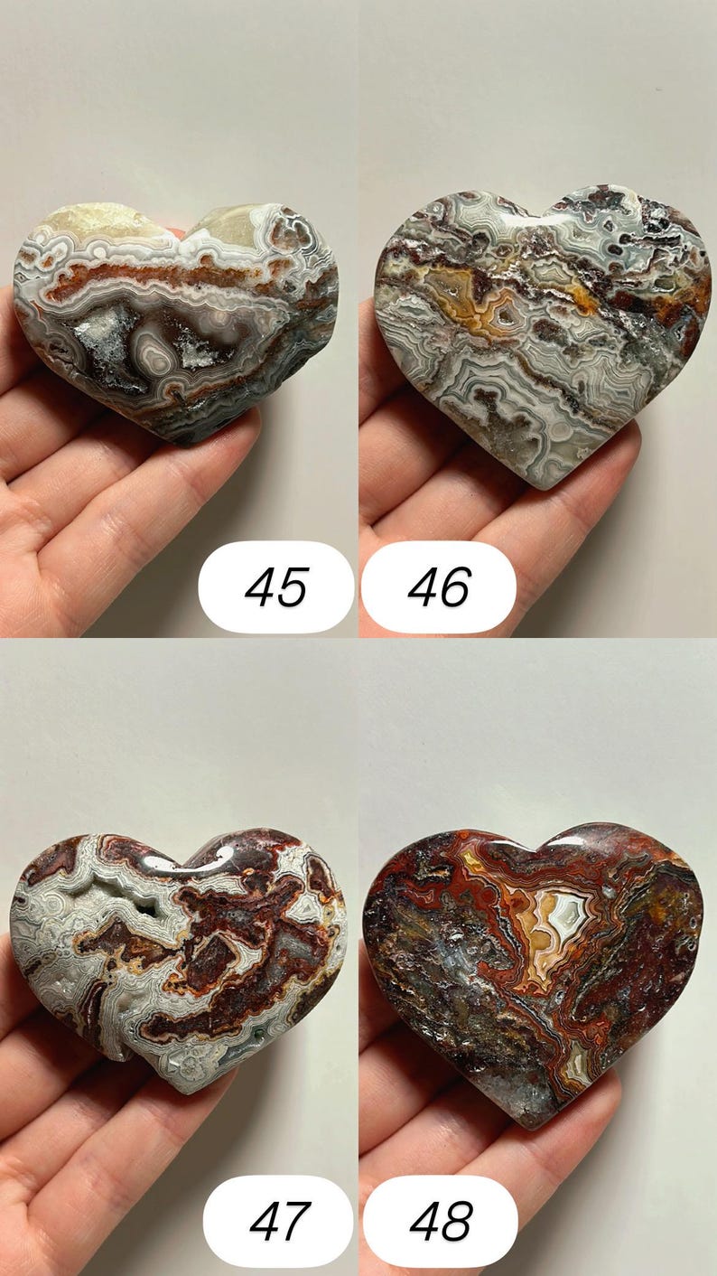 May include: Four heart-shaped stones with unique patterns and colors. The stones are held in hands and numbered 45, 46, 47, and 48. The stones feature a mix of brown, white, and gray hues, with intricate veining.