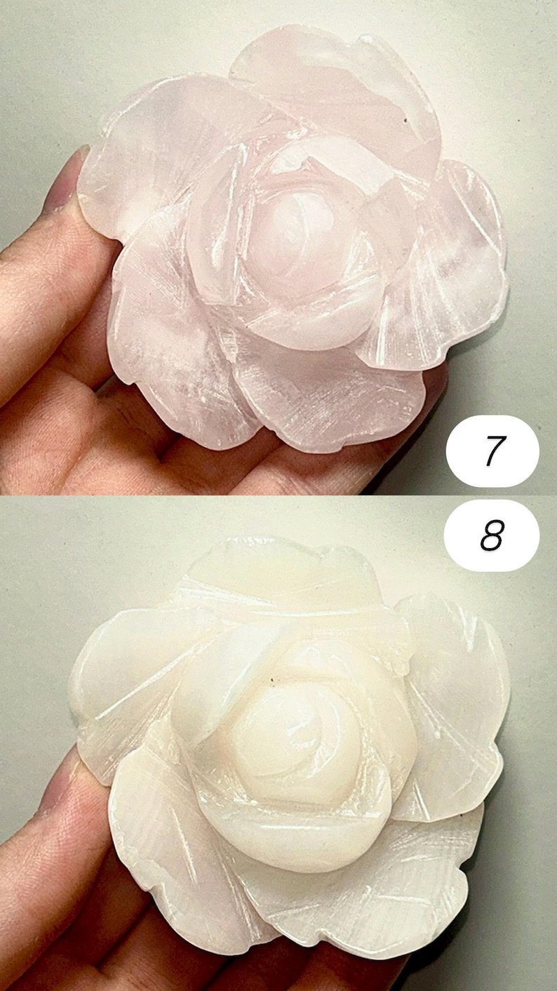 May include: Two carved rose-shaped gemstones. The top rose is a light pink color, while the bottom rose is a creamy white. The petals are detailed with carved lines. The gemstones are likely used for decorative purposes.