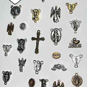 May include: A collection of religious charms and pendants in various shapes and sizes. The charms include crosses, angels, and heart-shaped designs, in silver and gold tones. The text "Faith" is visible on one charm.