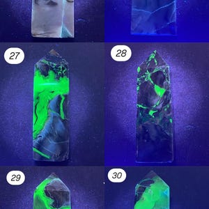 K&ouml;nnte beinhalten: Eine Sammlung von sechs fluoreszierenden Mineralproben, jeweils ein rechteckiges Prisma mit spitzer Spitze. Die Mineralien zeigen unter ultraviolettem Licht eine Vielzahl von Farben, darunter Gr&uuml;n, Schwarz und Grau. Die Proben sind von 25 bis 30 nummeriert.